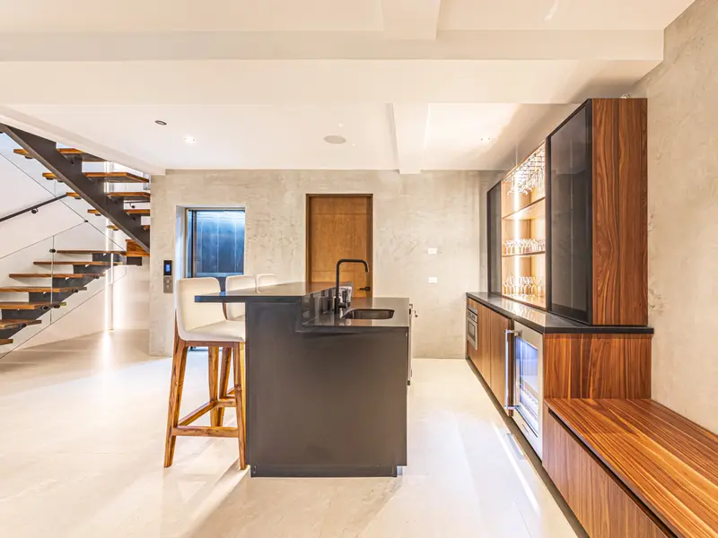 Wet bar with a dark stone counter and bar stools