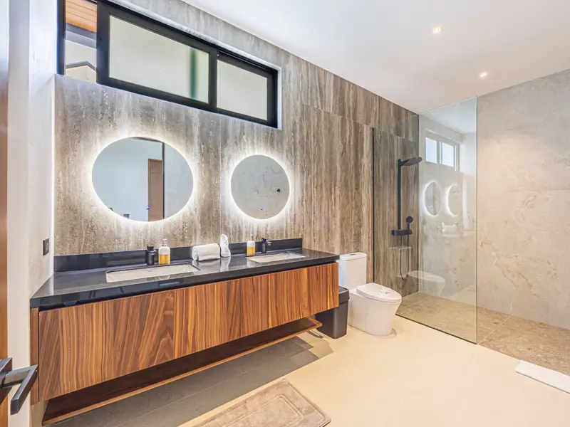 Twin backlit round mirrors above a walnut double vanity