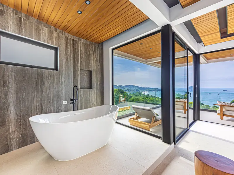Freestanding tub set beside a window onto the treetops