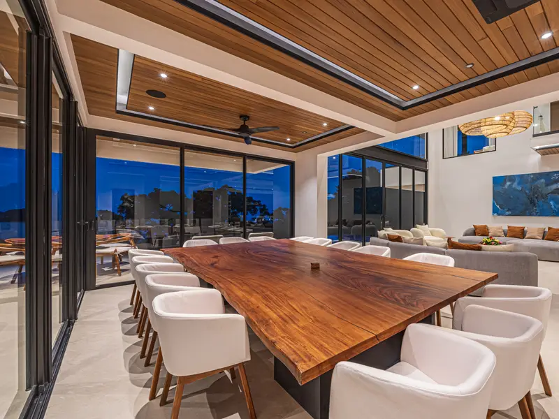 Long hardwood dining table set against the ocean view