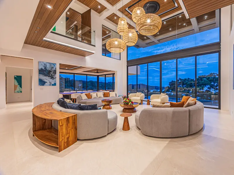 Double-height great room with sculptural rattan pendants opening to the Pacific