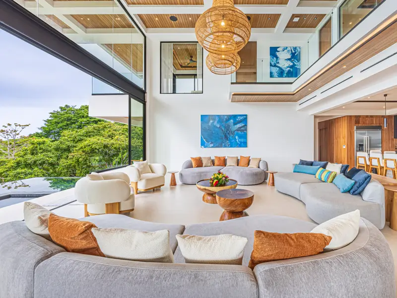 Curved sofa and low timber table framed by floor-to-ceiling glass