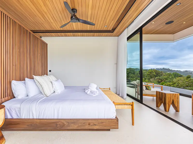 Bedroom framed by glass on two sides above the canopy