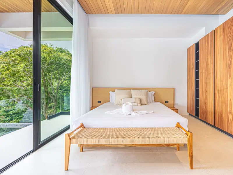 Bedroom with a full-height timber wardrobe wall and garden outlook