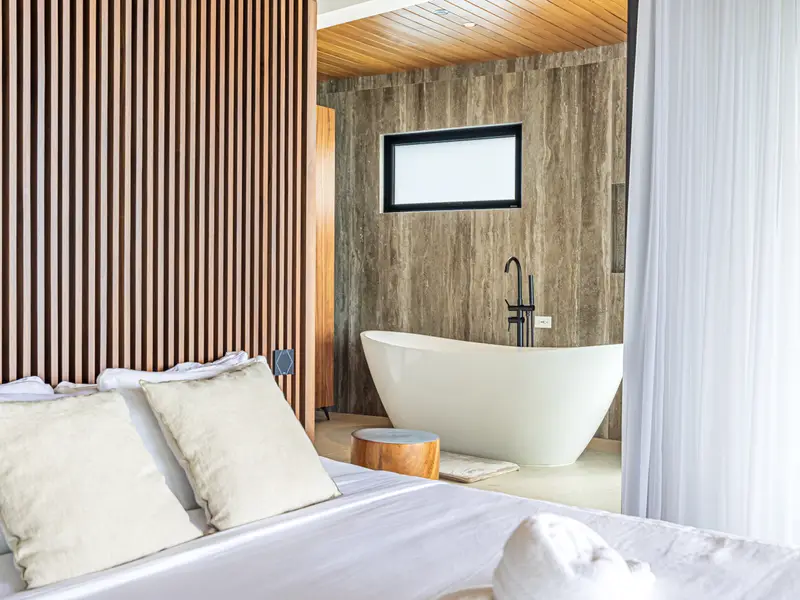 Bedroom with a freestanding tub behind a linen curtain