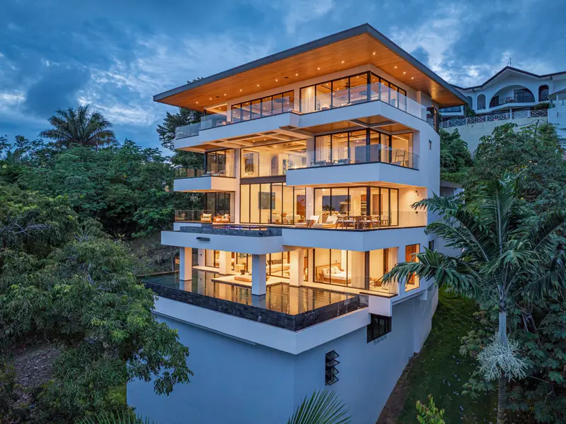 The villa lit from within at dusk